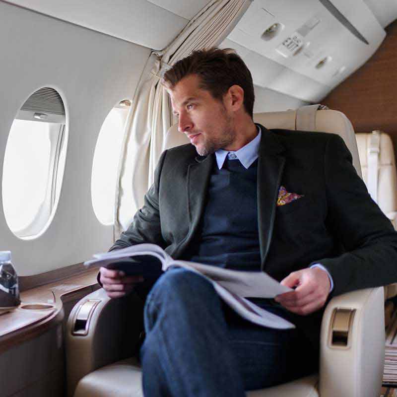 A man looks out the window of a private jet